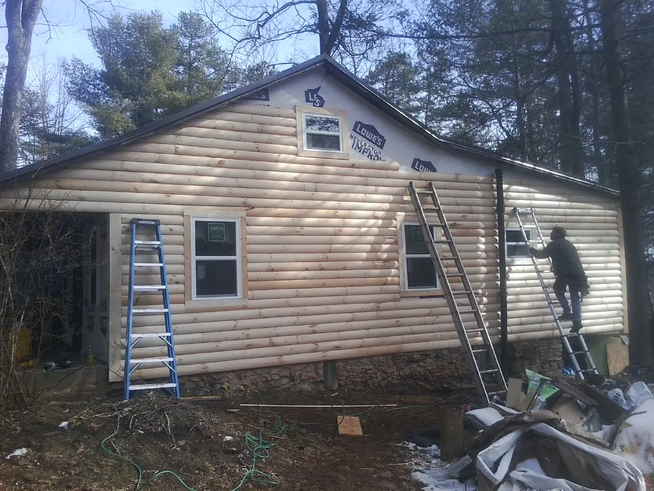 Ladders set against fresh log siding during an exterior remodel in Ellington