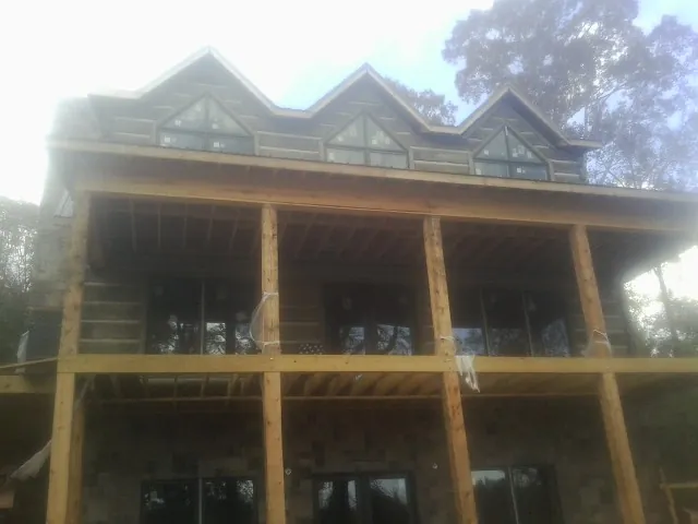 Dormers and porch framing on a large log home under construction — Roof Coating work by our crew in Ellington