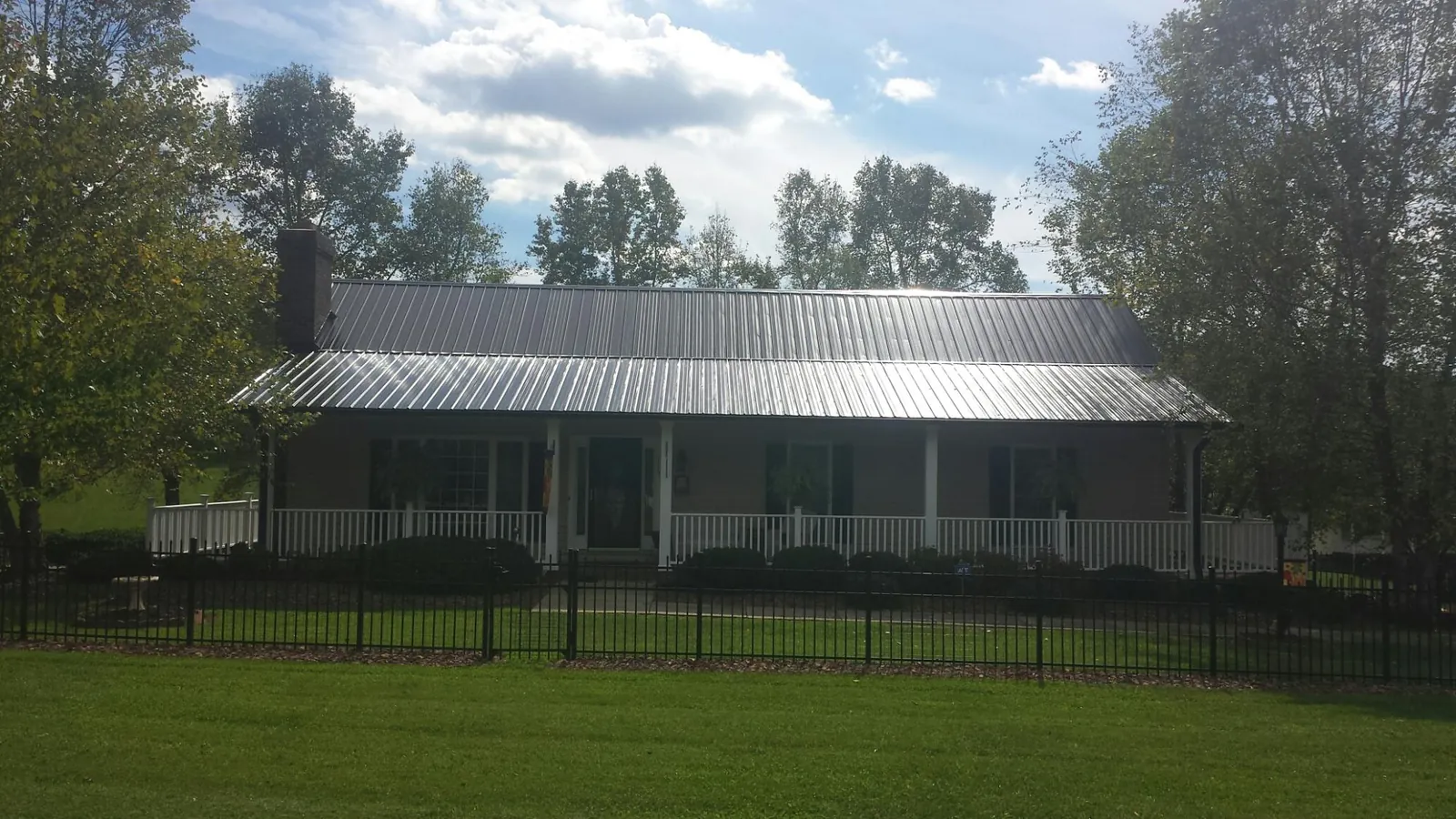 Gray metal roof on a brick ranch with a full width front porch — Gutter Guard Installation work by our crew in Ellington
